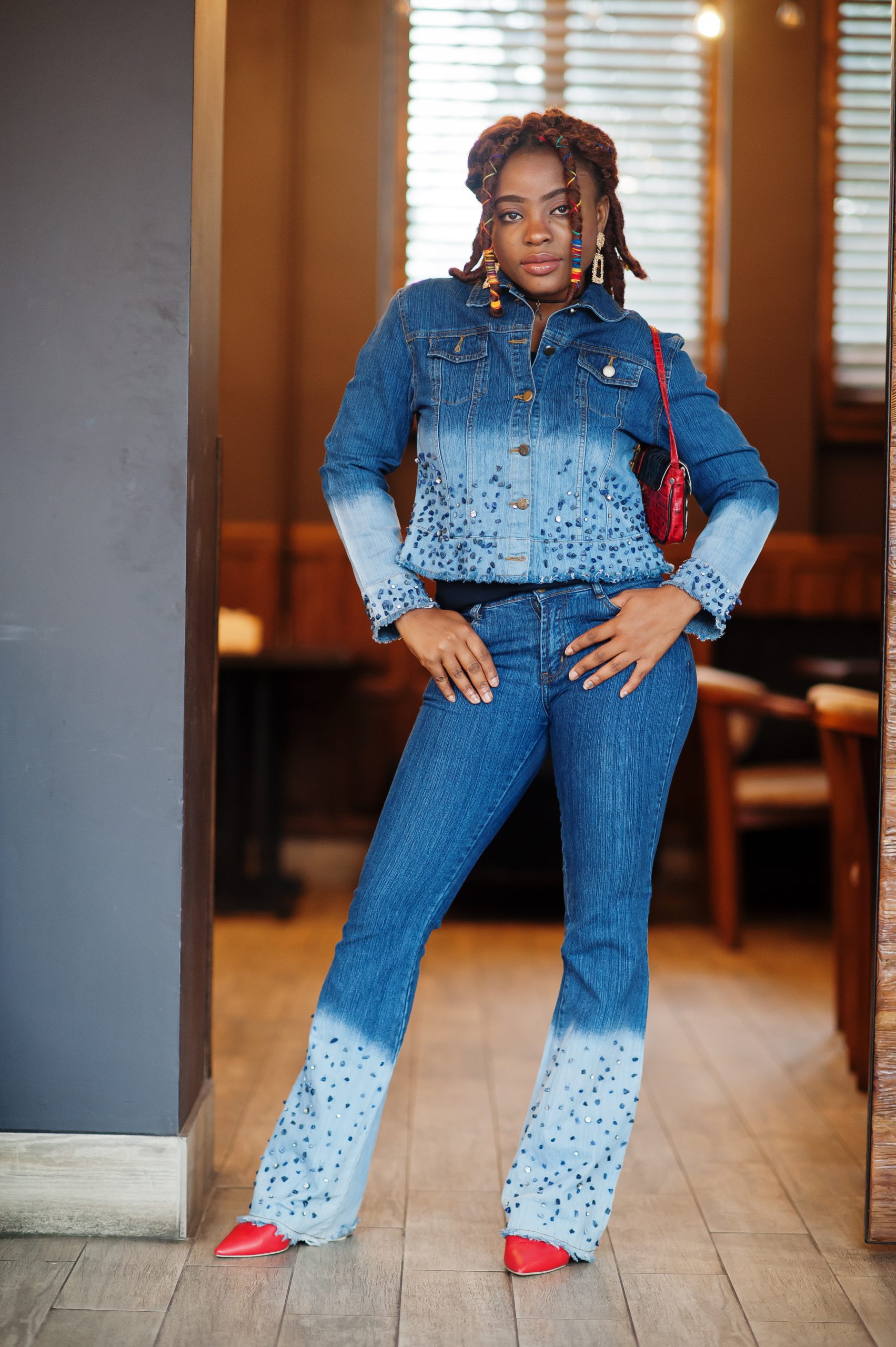 Lovely african american woman with dreadlocks in blue stylish jeans jacket at cafe. Beautiful cool fashionable black young girl indoor.